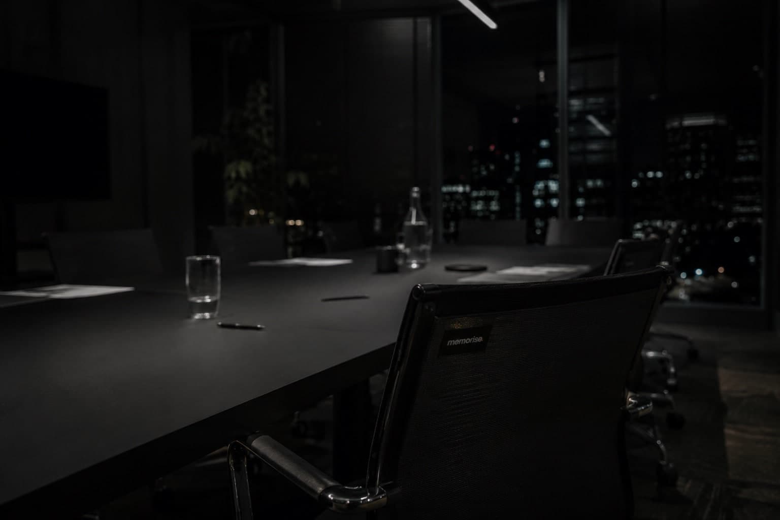 Fractional CMO meeting in empty dark boardroom with memorise chair and nocturnal city silhouette through windows